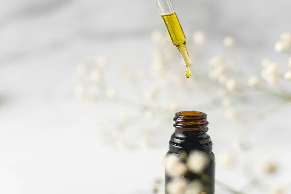 Woman applying aromatherapy oil skin care benefit oily blend to face with fingertips