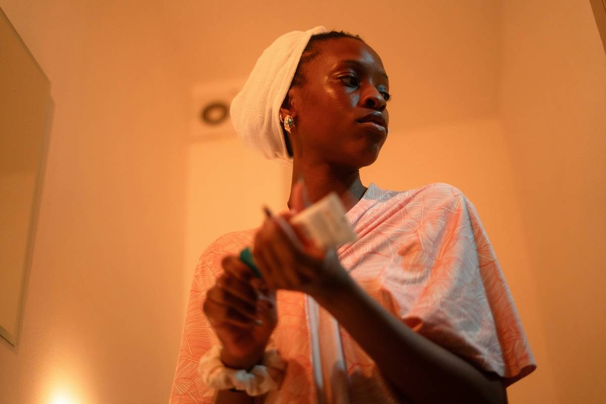 Woman applying body oil uses and benefits on damp skin after shower